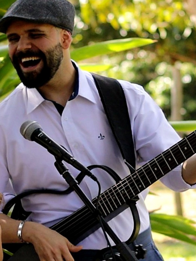 Davi D'Assunção tocando violão e cantando